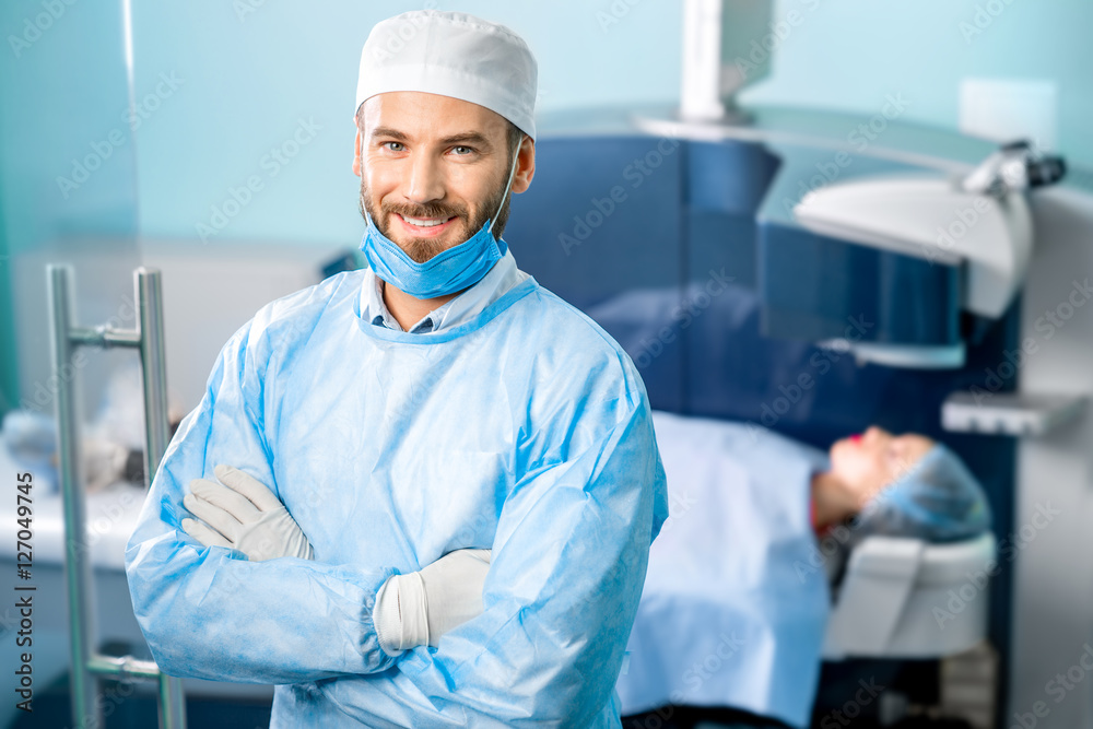 Portrait of eye surgeon in the operating room with patient and laser machine on the background. Laser vision correction