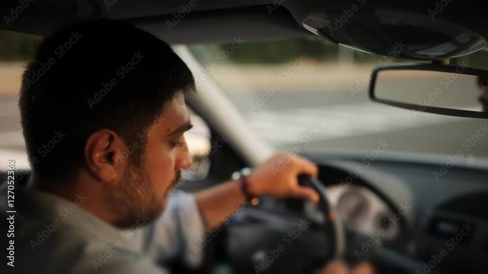 A male driver texting on a cellphone while driving