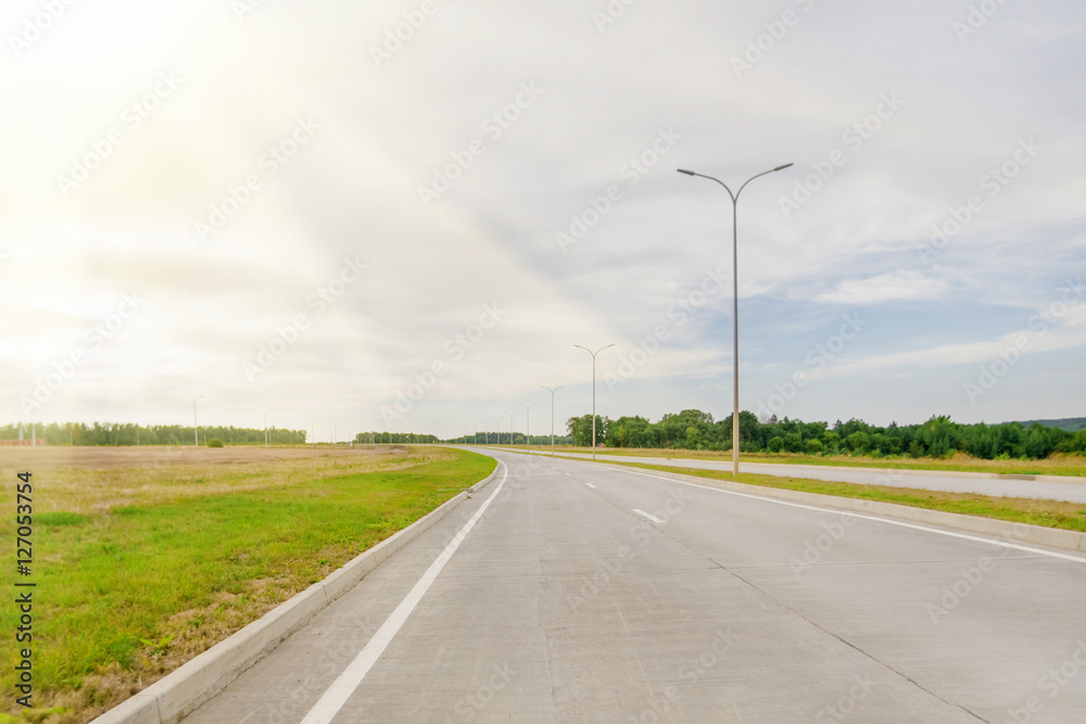 Asphalt road with a dividing strip and car in the sunlight Asphalt road with a dividing strip and car in the sunlight