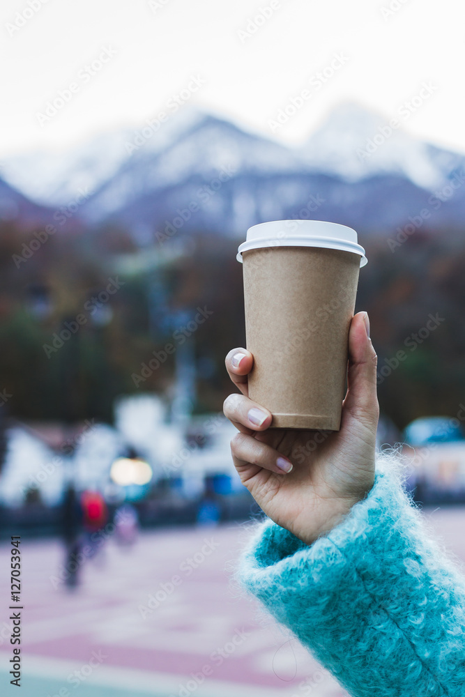 Girl's hand holding a cup of warming beverage with Mountain View Girl's hand holding a cup of warming beverage with Mountain View