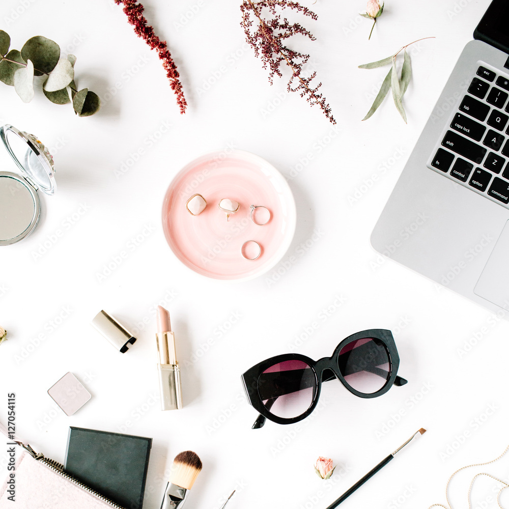 Flat lay, top view office table desk frame. feminine desk workspace with laptop, clutch, cosmetics, phone, sunglasses, lipstick rose buds on white background.