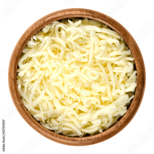 Shredded mozzarella pizza cheese in wooden bowl over white. Cheddar like semi hard Italian cheese made from milk, covered with corn starch. Isolated macro food photo close up from above.