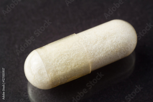 Glucosamine capsule, food supplement pills on glossy dark background, macro image. photo