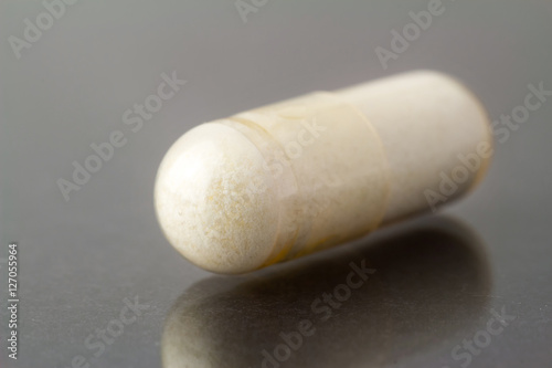 Glucosamine capsule, food supplement pills on glossy dark background, macro image. photo