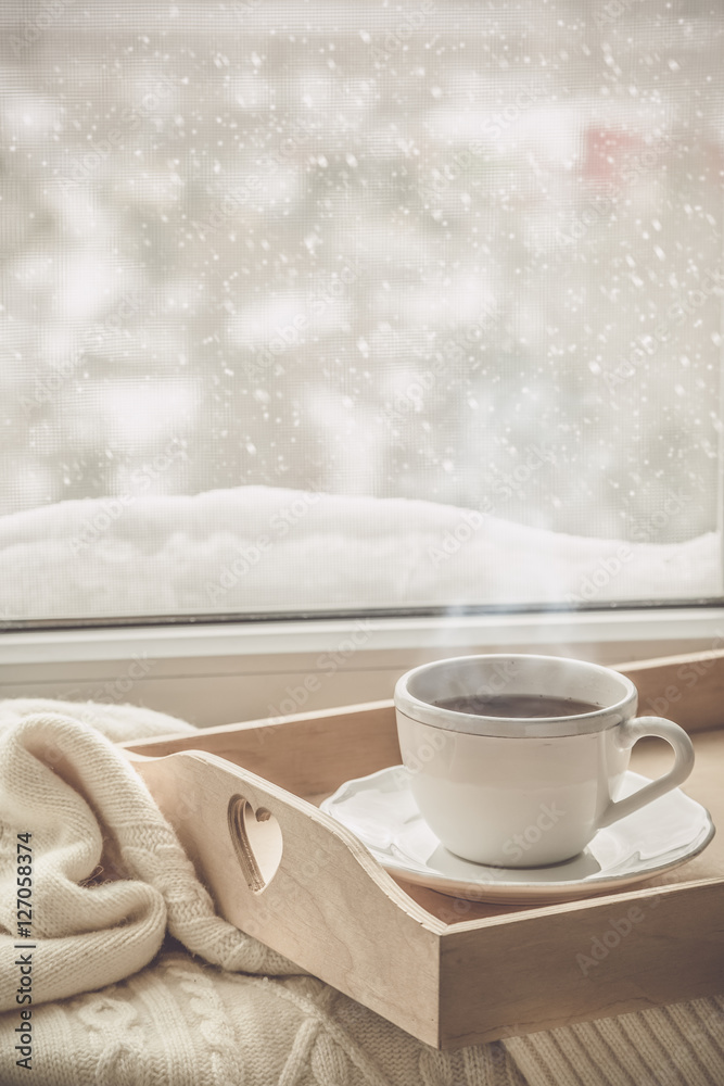 Tea on tray and sweater in from of snowing winter Tea on tray and sweater in from of snowing winter