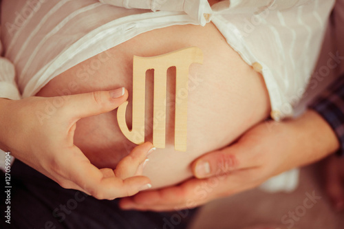 pregnant woman holding wooden letter near the tummy
