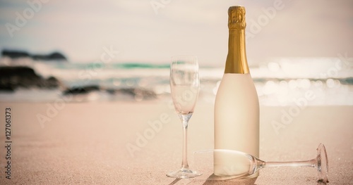 Champagne bottle and two flutes on sand