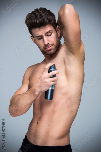 Man applying deodorant smiling 