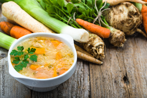 Vegetable soup in a bowl and fresh vegetables on wooden table photo