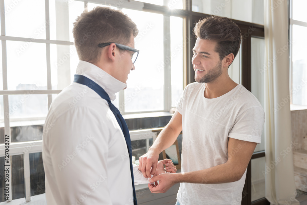 Fototapeta premium Handsome man helping his young boyfriend to dress