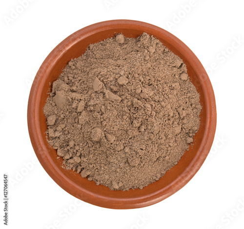 Cocoa powder in a small bowl top view isolated on a white background.