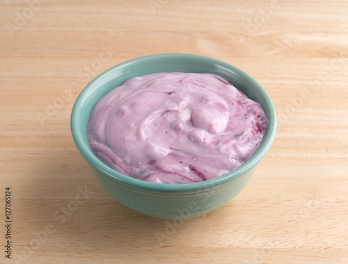 Bowl of blueberry gourmet yogurt on a wood table top.