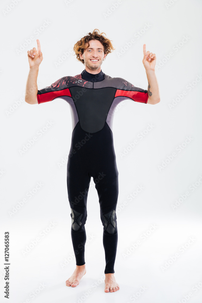 Smiling happy sportsman in diving suit pointing fingers up Smiling happy sportsman in diving suit pointing fingers up