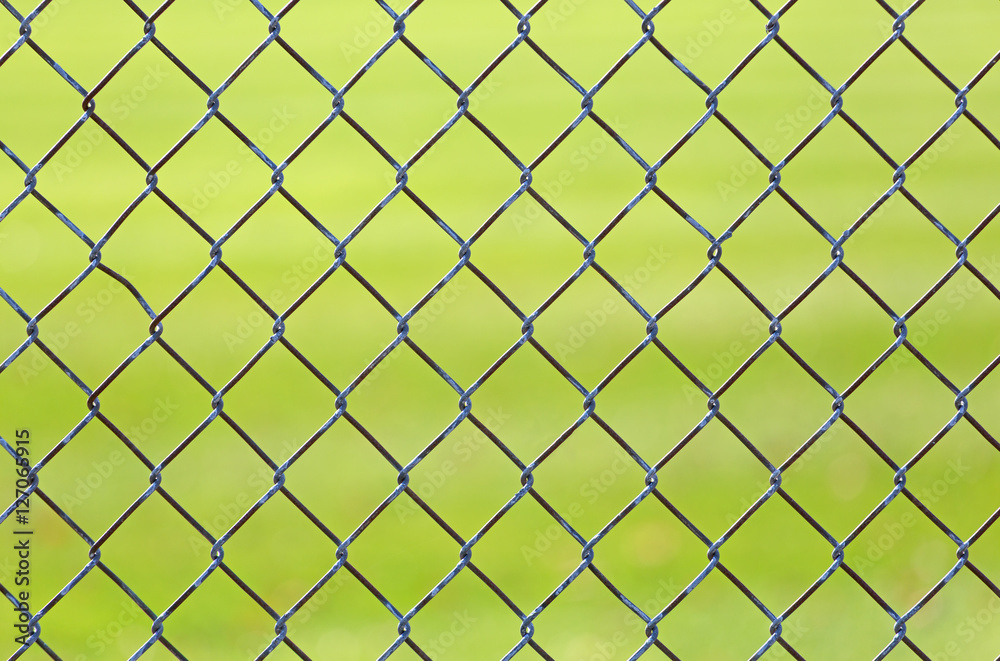 Chain link fence with green grass from a baseball field in background. Chain link fence with green grass from a baseball field in background.