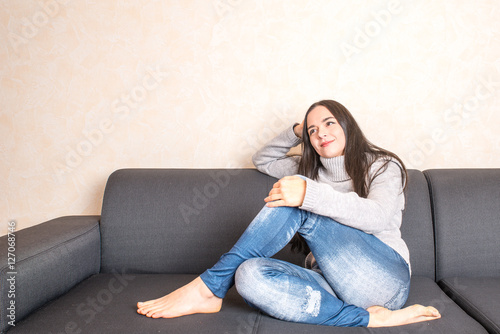 Woman with long black hair sitting at a sofa
