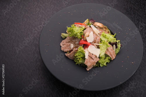 salad of veal, cheese and red pepper on black plate