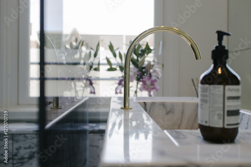 detail of a modern, stylish bathroom with a tap and soap and flowers photo