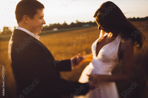 beautiful and young bride and groom standing in a field