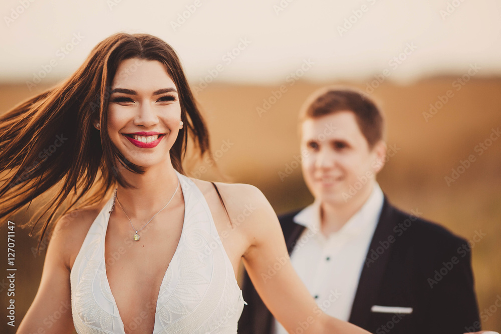 happy and young bride and groom standing together outdoors happy and young bride and groom standing together outdoors
