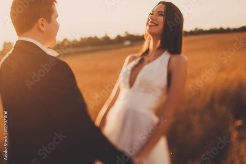 beautiful and young bride and groom standing in a field