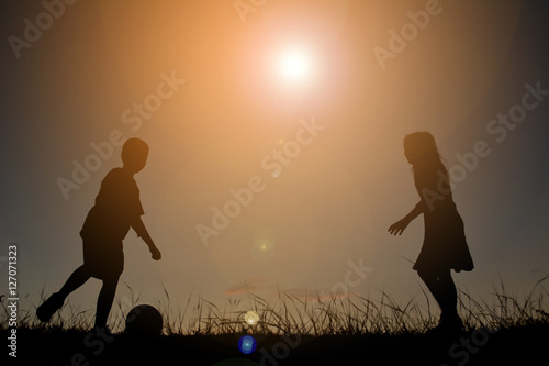 Silhouette children playing football on the sky sunset. Time on holiday