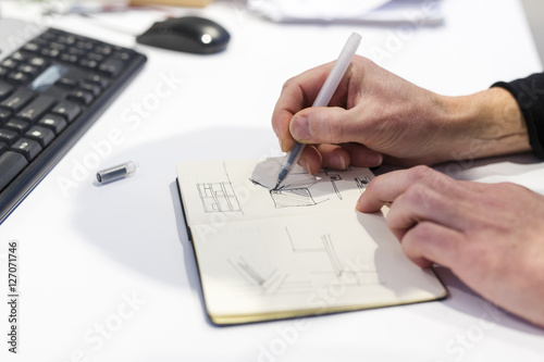 The Netherlands, Utrecht. Inside the factory of a Dutch design furniture brand.  Designer sketching in his notebook.