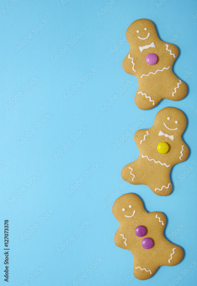 Hand decorated gingerbread men on a bright blue background with blank space at side Hand decorated gingerbread men on a bright blue background with blank space at side