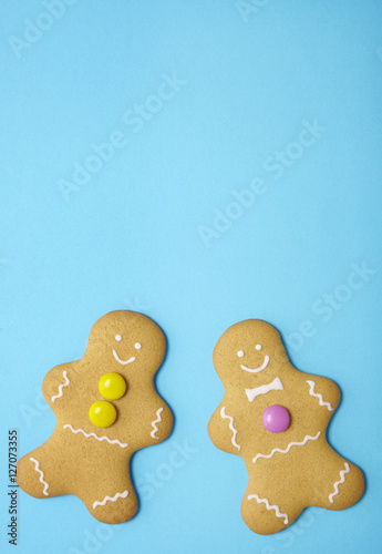 Hand decorated gingerbread men on a bright blue background with empty space above
