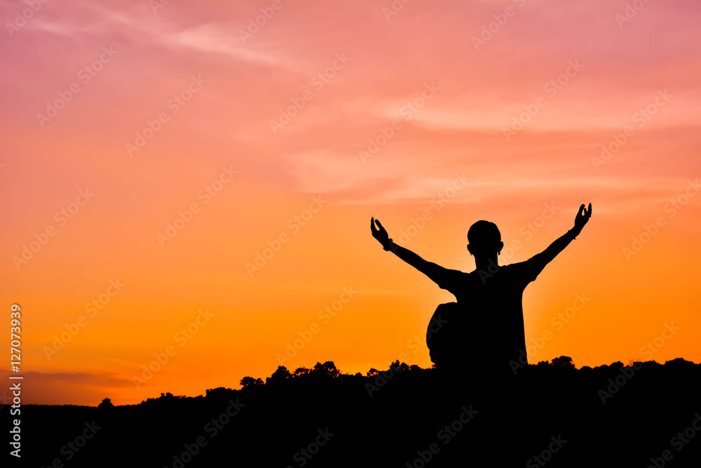 Silhouette of man with backpack open hand on the sky sunset back