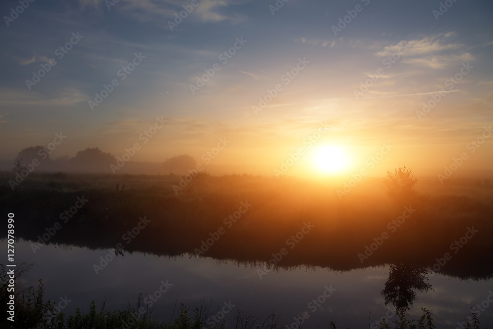 wonderful dramatic scene. fantastic foggy sunrise over the meadow with colorful clouds on the sky. picturesque rural landscape, misty morning. color in nature. beauty in the world