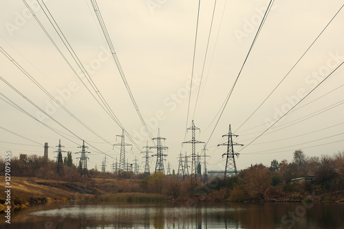 Coal power station in beautiful area full of trees and lake, mirror reflection of energetic pole and power station with chimneys, synergy of industry and nature