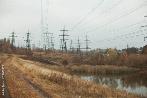 Coal power station in beautiful area full of trees and lake, mirror reflection of energetic pole and power station with chimneys, synergy of industry and nature