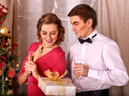 Couple on party near Christmas tree. Black and white retro. Young people decoration Christmas tree. Girl drink champagne. Man give gift box. photo