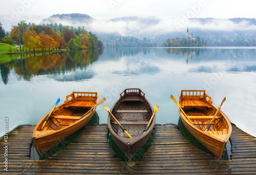 Three boats moored on Bled lake at foggy autumn day