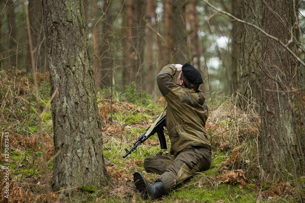 a military man in the woods with a Kalashnikov assault rifle, autumn forest with no leaves, green form, No face.