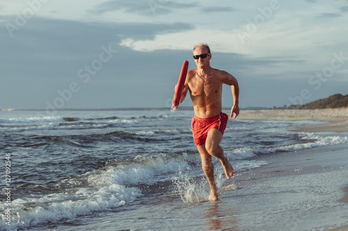 lifeguard on the beach with glasses, with a life buoy, wet sand and sea at sunset