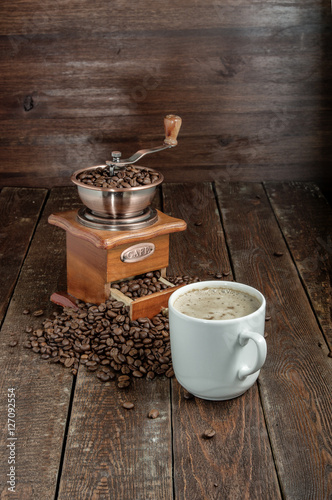 Vintage coffee grinder with cup coffee and beans on rustic table