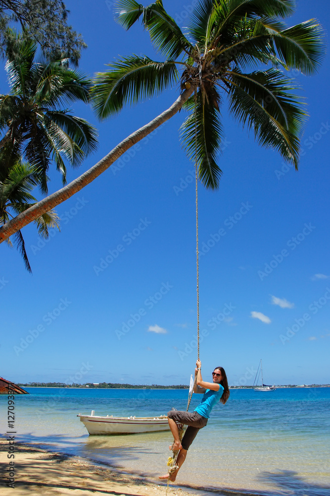 Young woman swinging on a rope swing at Pangaimotu island near T