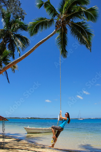 Young woman swinging on a rope swing at Pangaimotu island near T photo