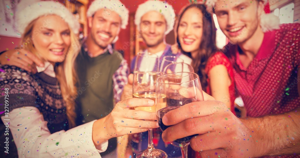 Composite image of friends wearing christmas hats while toasting Composite image of friends wearing christmas hats while toasting