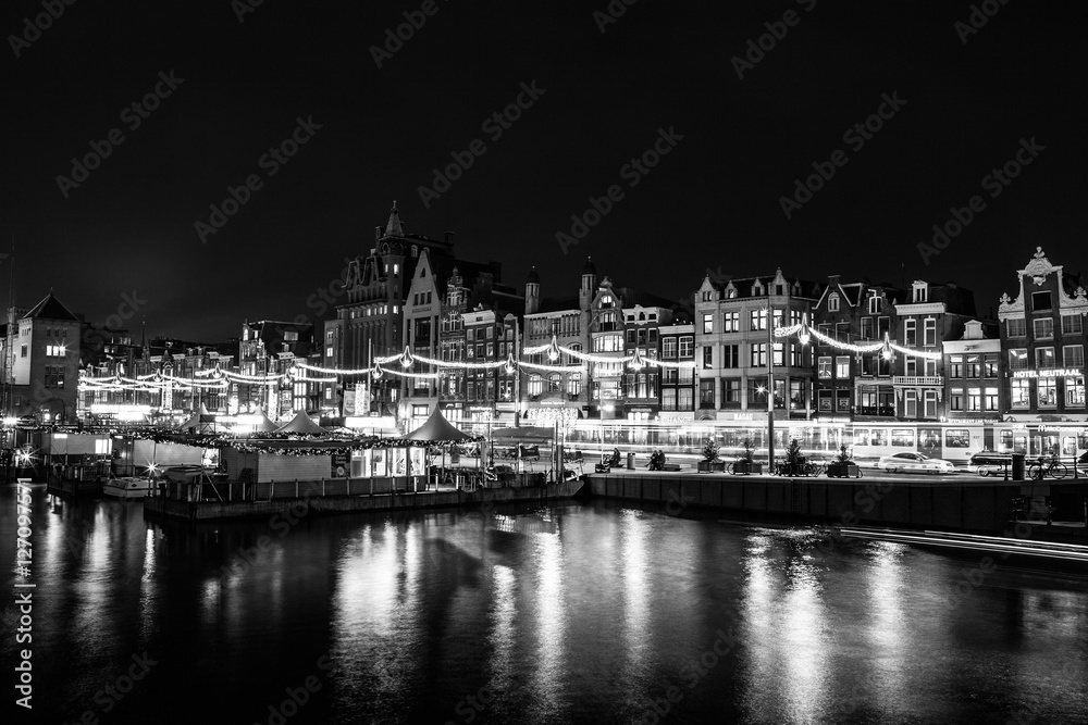 AMSTERDAM, NETHERLANDS - DECEMBER 14, 2015: Black-white photo of cruise boat moving on night canals of Amsterdam in Amsterdam, Netherlands.