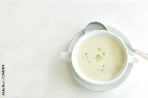 Cream soup in white cup on white table background with space for text here photo