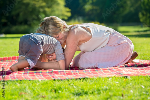 Mother playing with little boy on blanket. photo