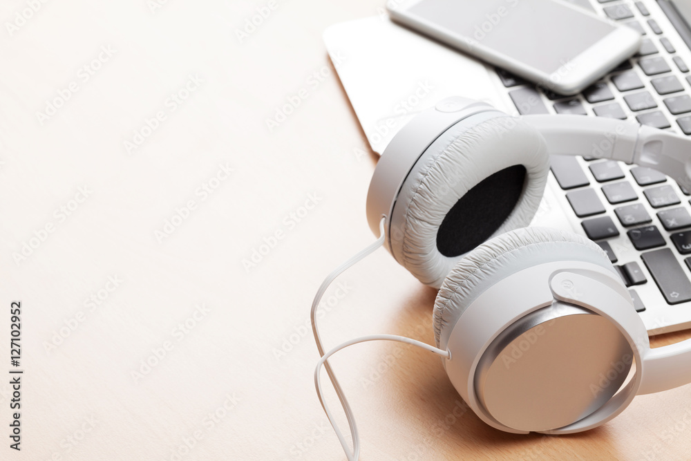 Obraz premium Headphones over laptop on wooden desk table
