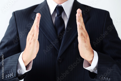 Businessman gesturing with his hands on grey background