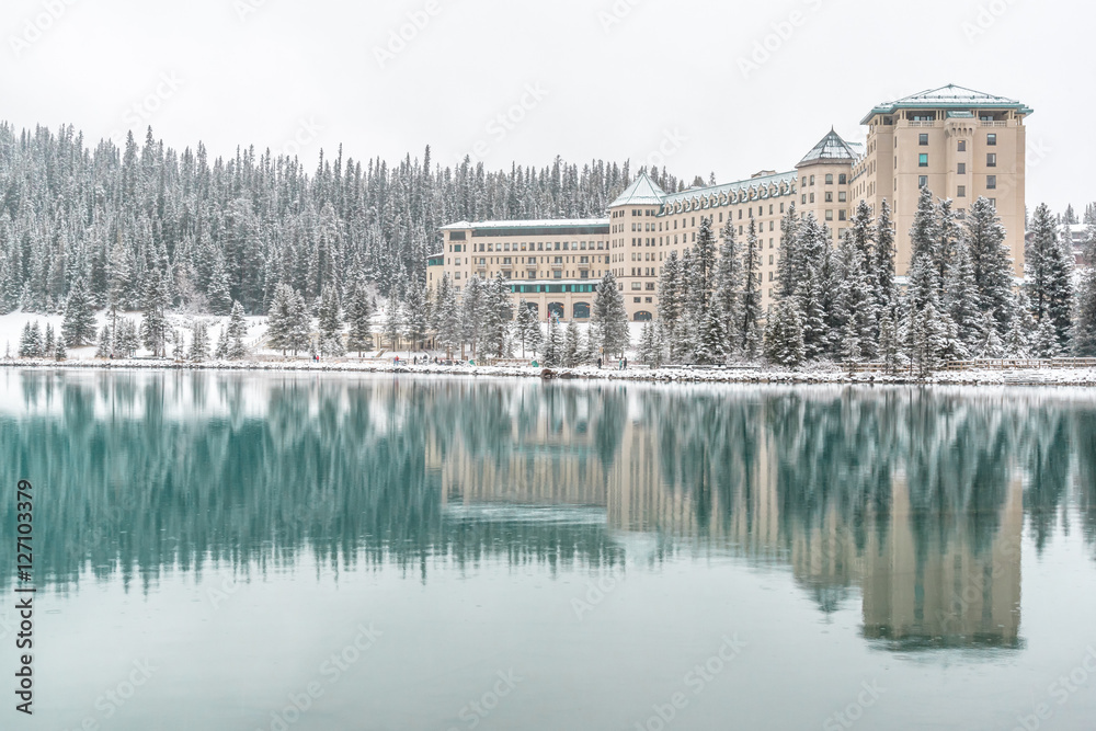 Fototapeta premium Fairmont Chateau Lake Louise with Winter Reflection in Unfrozen Lake, Banff National Park, Alberta, Canada