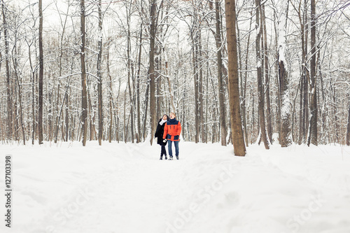 love, relationship, season, friendship and people concept - man and woman walking in winter forest