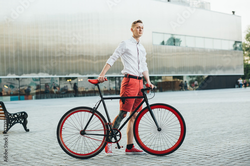 Hipster with red bycicle and tattoo on leg