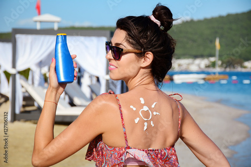 smiling woman with sun-shaped sun cream.Sun Drawn On Woman's Shoulder With Sun Protection Cream