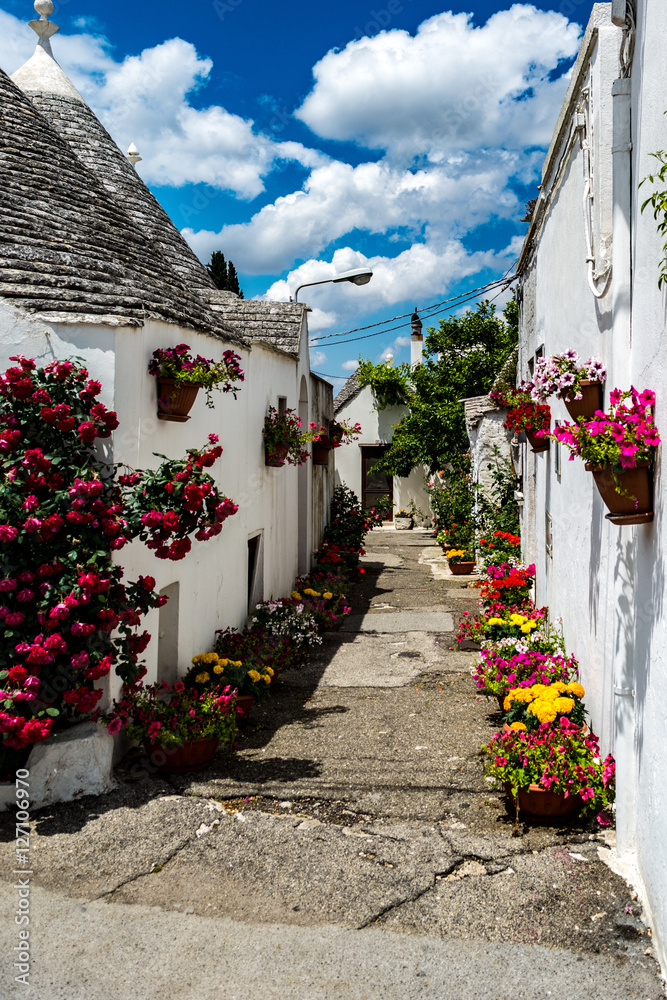 Street covered with spring flowers in Alberobello, Italy